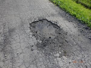 道路に穴ぼこが空いており破片が散らばっている写真