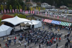 屋外のステージを多くの人が観覧しているのを上から撮った写真