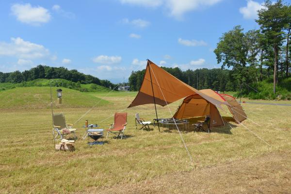 広い芝生の上に茶色いテンや椅子トが設置されている写真
