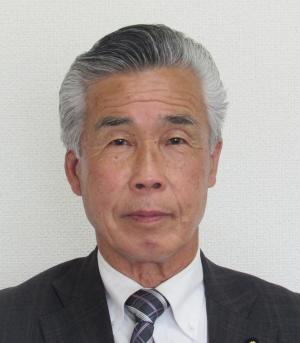 黒いスーツを着た佐野英俊氏の写真