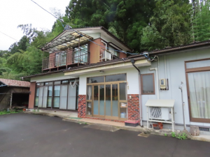 山あいに建つ二階建て住宅の外観の写真