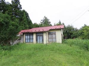 草地に建つ赤い屋根の平屋住宅の外観の写真