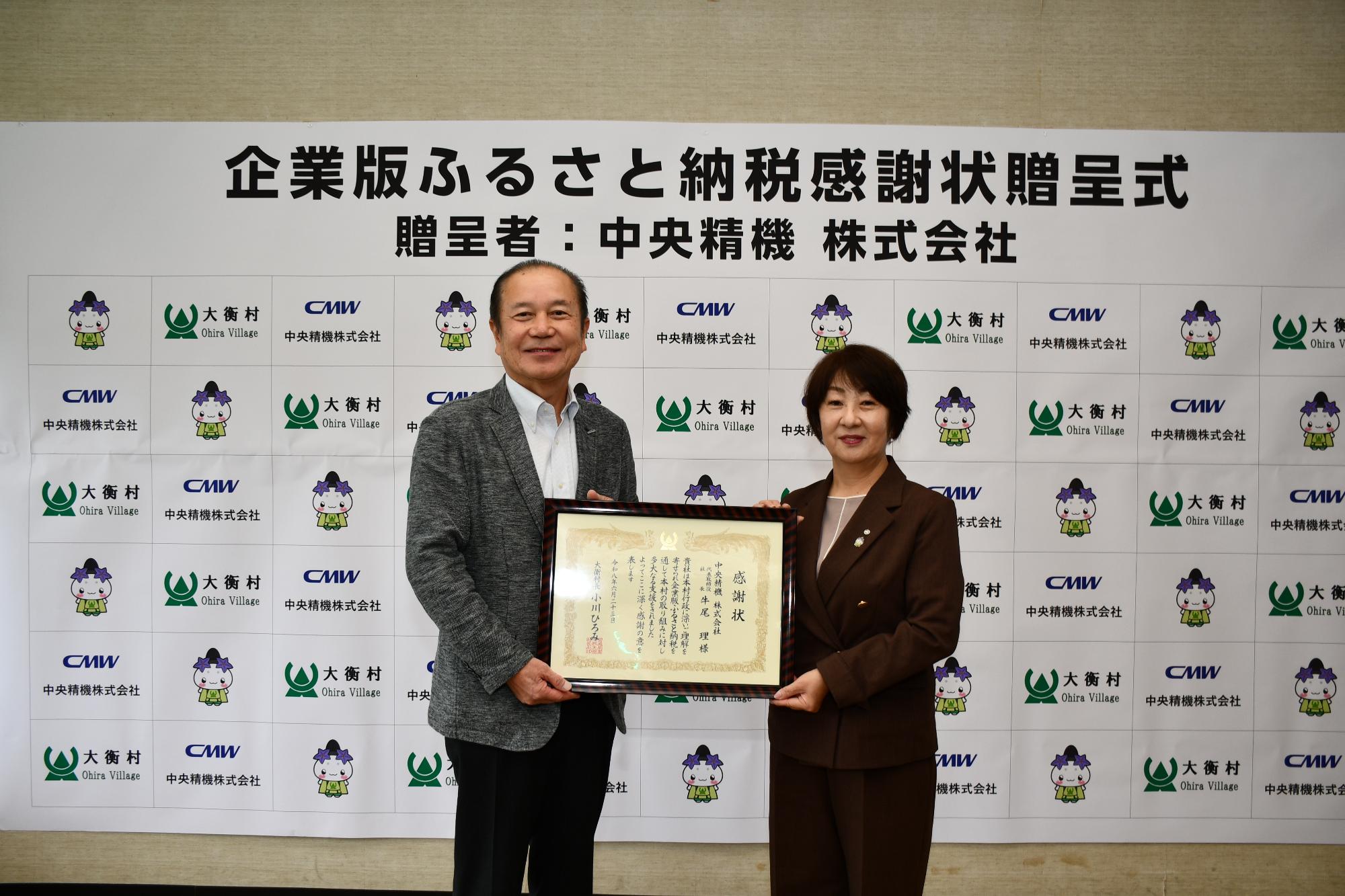中央精機株式会社感謝状贈呈式の写真。社長と村長が感謝状をもっているシーン。