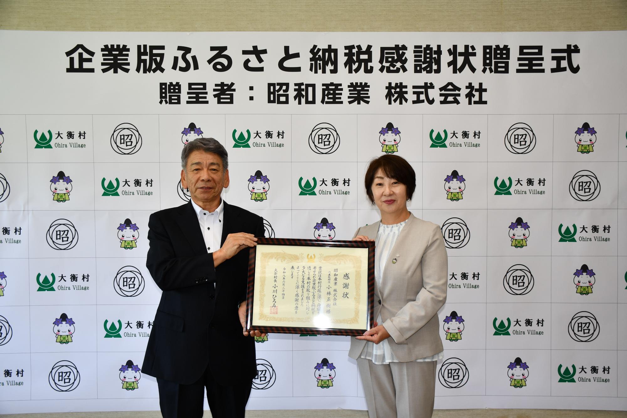 昭和産業株式会社感謝状贈呈式の写真。社長と村長が感謝状をもっているシーン。