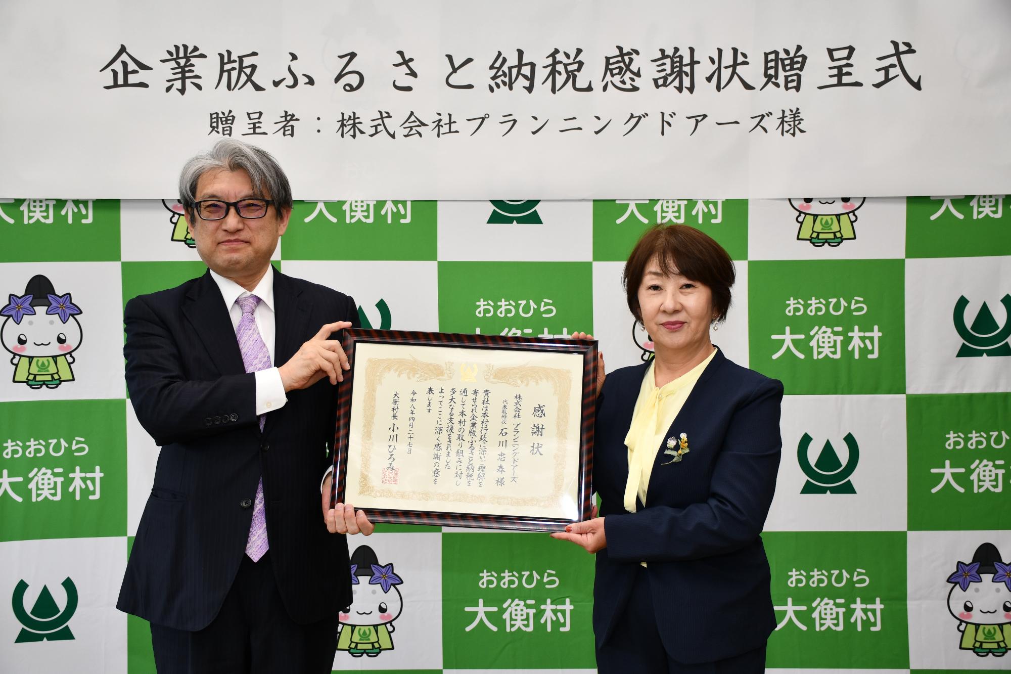 村長とプランニングドアーズ関係者が感謝状を手にもっている写真