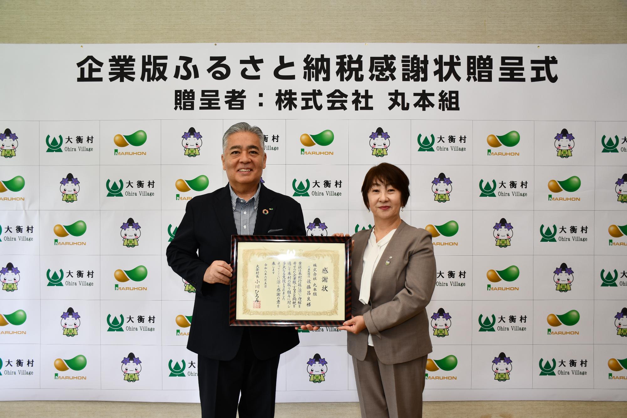 株式会社丸本組感謝状贈呈式の写真。社長と村長が感謝状をもっているシーン。