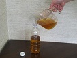 こした油をペットボトルに入れている写真
